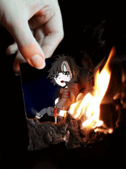 a person is holding a piece of paper with a cartoon character on it in front of a fire