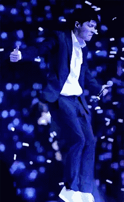 a man in a suit is jumping in the air with a microphone in his hand