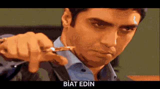 a man is pointing at the camera with the word biat edin written below him
