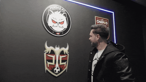a man in a black jacket stands in front of a persas fc logo