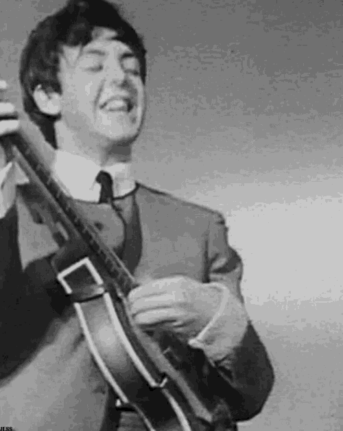 a man in a suit and tie is playing a guitar on stage .