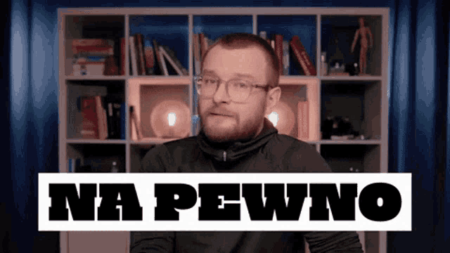 a man wearing glasses stands in front of a bookshelf with the words na pewno written on it