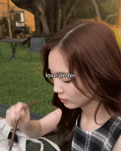 a woman is sitting in the grass with the words love de fer above her