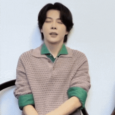 a man with his eyes closed wearing a sweater and green shirt