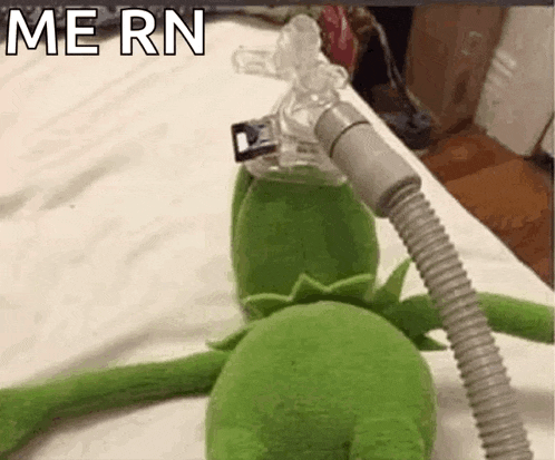 kermit the frog is laying on a bed with an oxygen mask on his face .