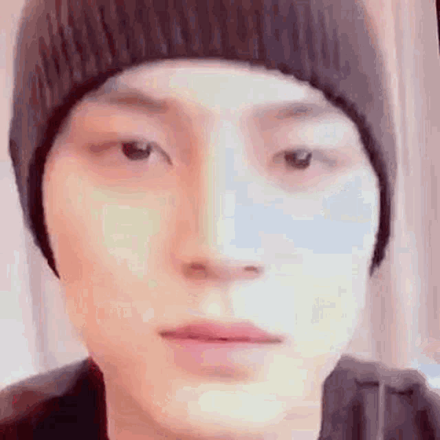 a close up of a person wearing a beanie and looking at the camera .