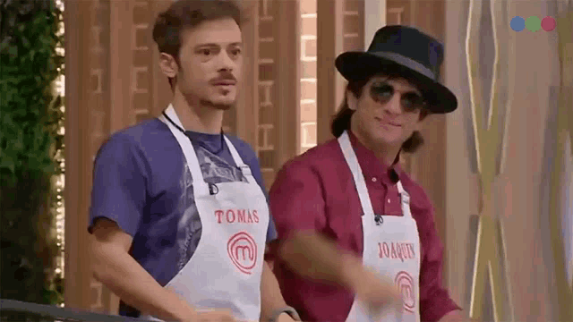two men wearing aprons with the letters m on them