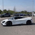 a white sports car is parked in a parking lot next to a truck .