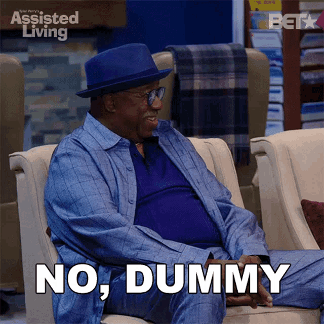 a man is sitting on a couch with the words no dummy written on his chest