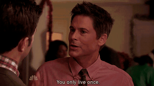 a man in a pink shirt and tie is talking to another man and says you only live once