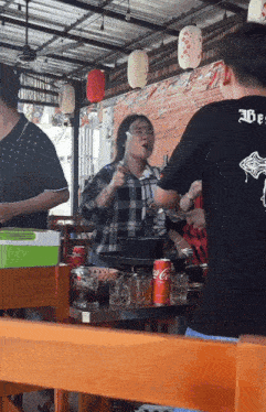 a man wearing a black shirt that says " abe " stands in front of a table with coca cola cans on it