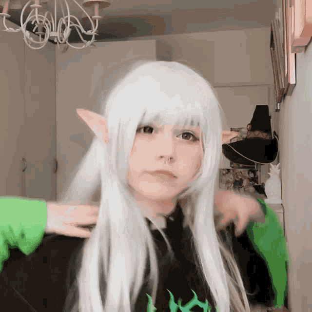 a girl with long white hair and elf ears is wearing a green sweater