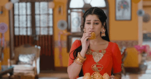 a woman in a red dress is eating a bread roll