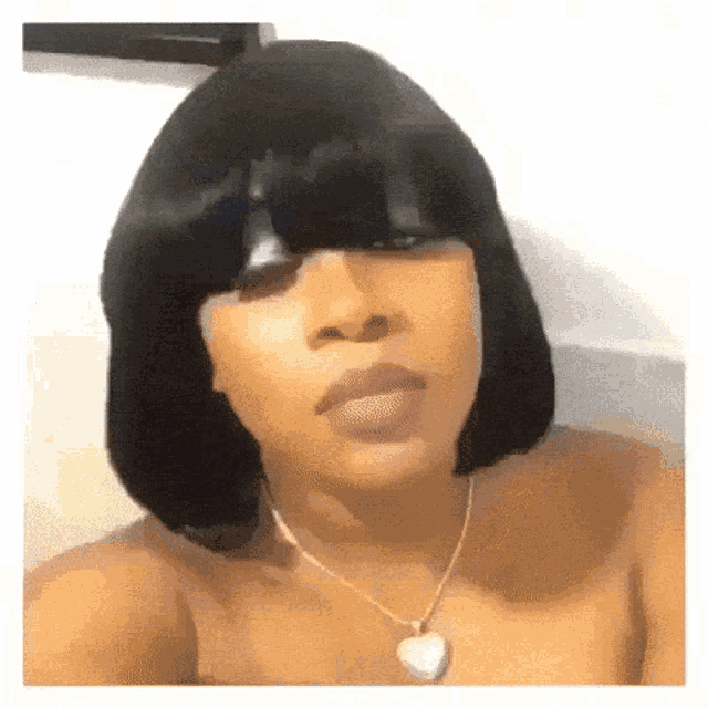 a woman is wearing a wig and a necklace with a heart pendant .