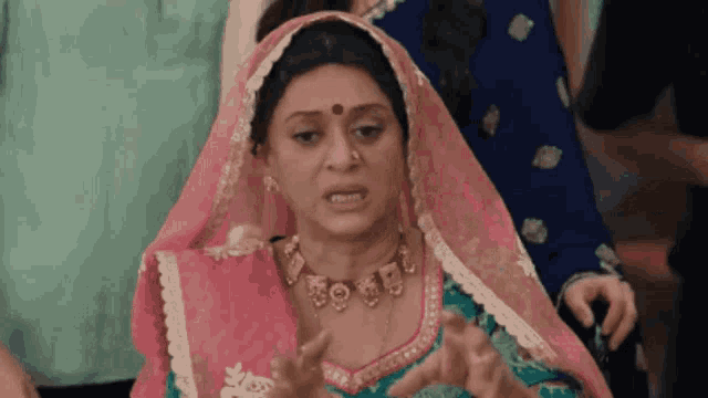 a woman wearing a pink veil and a necklace is making a face .