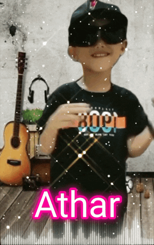 a young boy wearing sunglasses and a black shirt with the name athar