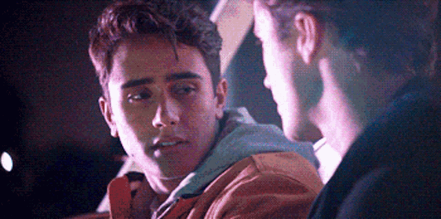 two young men are sitting next to each other in a dark room .