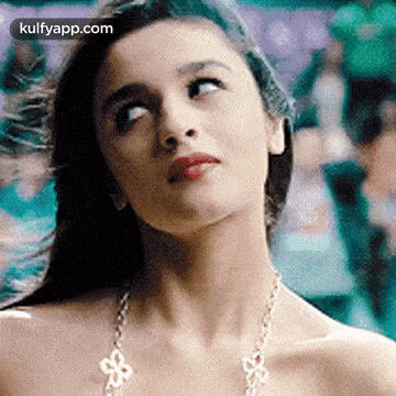 a close up of a woman wearing a necklace and looking up at the sky .