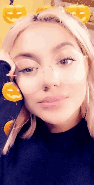 a woman wearing glasses and a nose ring with pumpkins in the background