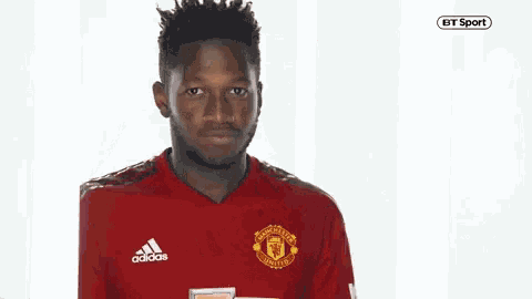 a man wearing a red adidas manchester united jersey making a funny face