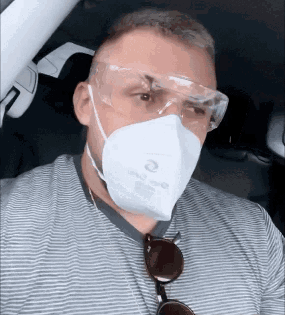 a man wearing a n95 mask and goggles looks at the camera