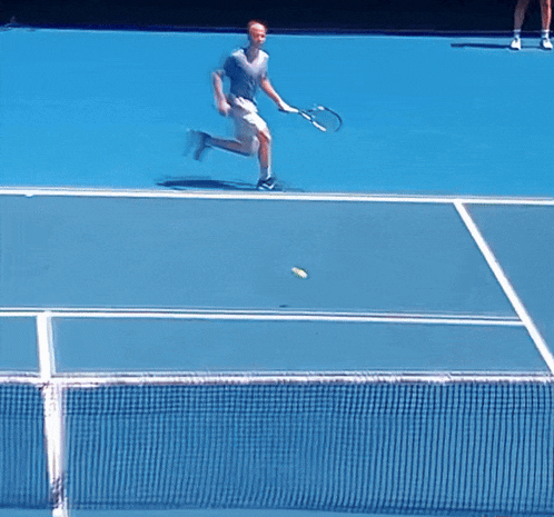 a man playing tennis on a blue court
