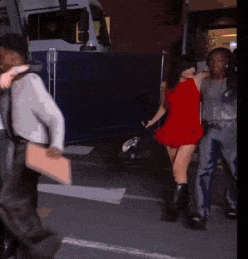 a woman in a red dress is walking across the street