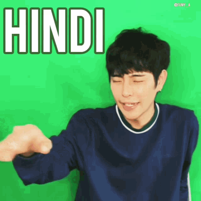 a man in a blue shirt is giving a fist bump in front of a green screen that says hindi on it