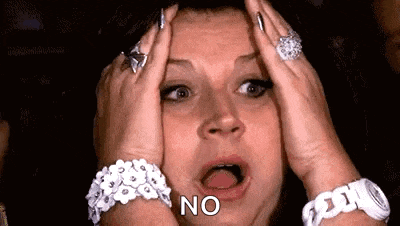 a woman with a surprised look on her face is holding her head with her hands and saying no .