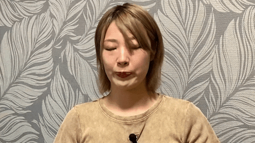 a woman is making a funny face in front of a leafy wallpaper