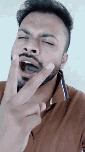 a man with a beard is making a peace sign with his finger