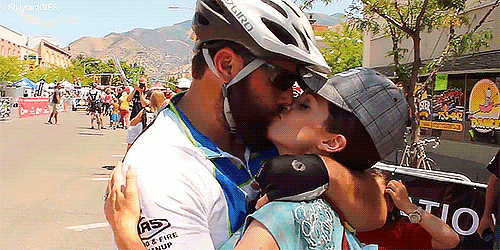 a man wearing a giro helmet kisses a boy on the cheek