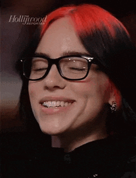 a close up of a woman wearing glasses and smiling with her eyes closed .
