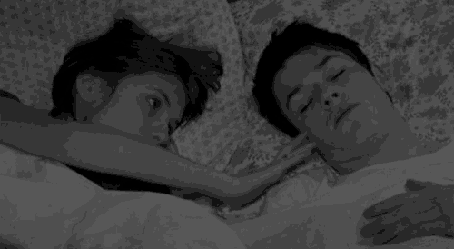 a man and a woman are laying in bed together .