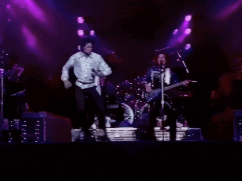 a man in a white shirt is dancing on stage