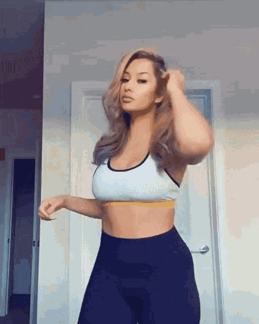 a woman in a sports bra and black pants is standing in a room