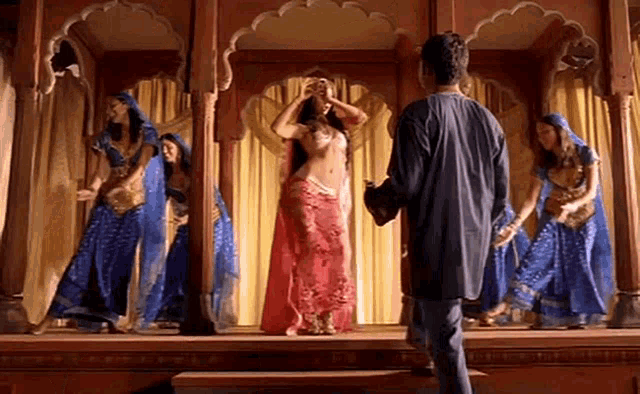 a man is standing in front of a group of belly dancers in traditional costumes .