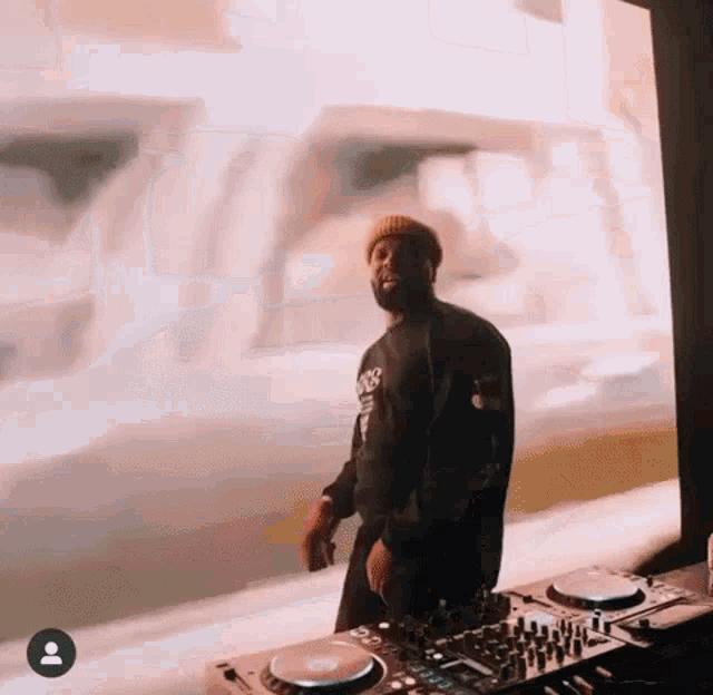 a man with a beard is standing in front of a dj mixer .