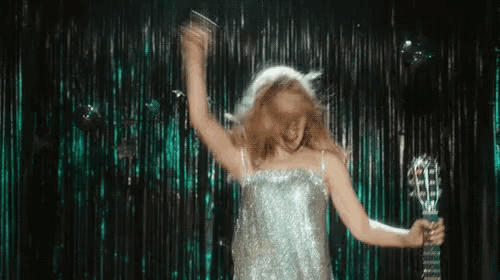 a woman in a sequined dress is holding a guitar and dancing on a stage .