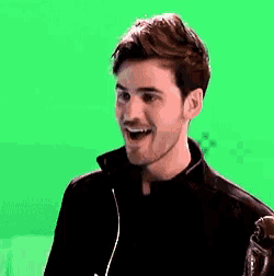 a young man is smiling in front of a green screen .