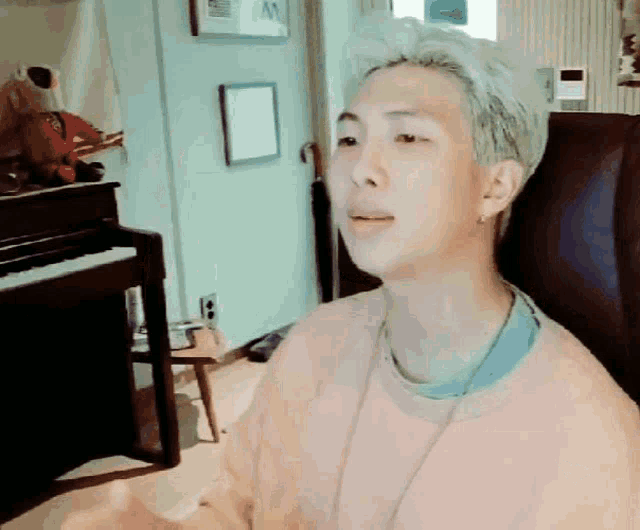a man with white hair is sitting in front of a piano in a living room .