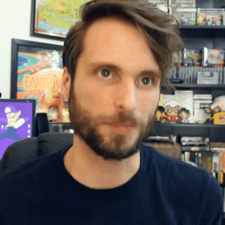 a man with a beard is wearing a black shirt and looking at the camera
