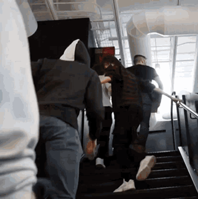 a group of people are walking up a set of stairs with one wearing a hoodie