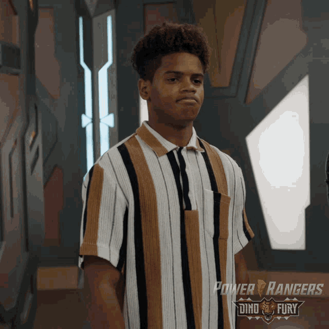 a man in a power rangers shirt stands in front of a wall