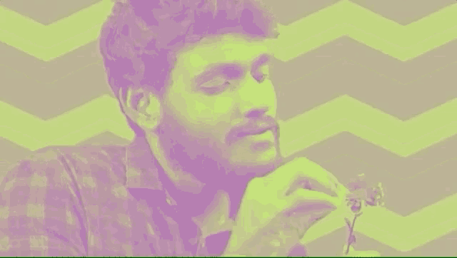 a man with a beard is holding a flower in his hand and looking down .