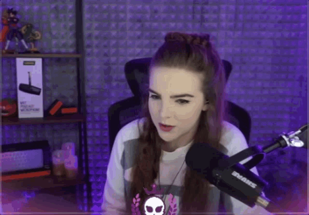 a woman is sitting in front of a shure microphone in a purple room