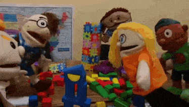 a group of puppets are playing with blocks on a wooden table .