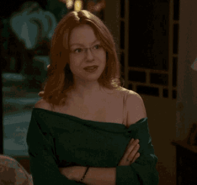 a woman wearing glasses and a green off the shoulder top