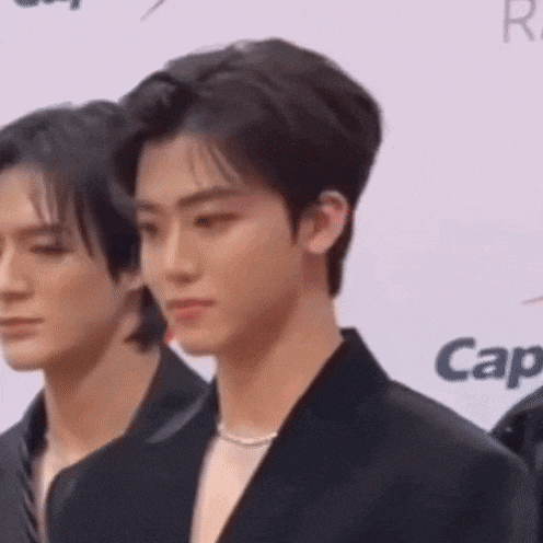 a man in a black suit is standing next to another man in a black suit .