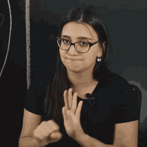 a woman wearing glasses and a black shirt with the word " dificil " on it